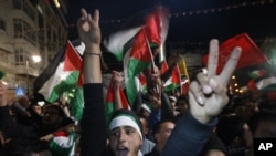 Palestinians celebrate as they watch a screen showing the U.N. General Assembly vote on a resolution to upgrade the status of the Palestinian Authority to a non-member observer state, in the West Bank city of Ramallah, Nov. 29, 2012.