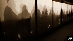 Migrants are silhouetted as they warm themselves inside a waiting tent to get an appointment at the central registration center for refugees and asylum seekers LaGeSo (Landesamt fuer Gesundheit und Soziales - State Office for Health and Social Affairs) in Berlin, Jan. 6, 2016. 