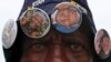 A street vendor offers buttons with pictures of Nelson Mandela outside the house where the anti-apartheid icon once lived in the township of Soweto, Dec. 9, 2013.