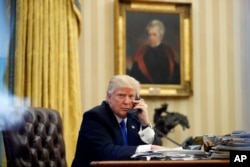 FILE - President Donald Trump speaks on the phone with Prime Minister of Australia Malcolm Turnbull in the Oval Office of the White House, Jan. 28, 2017.