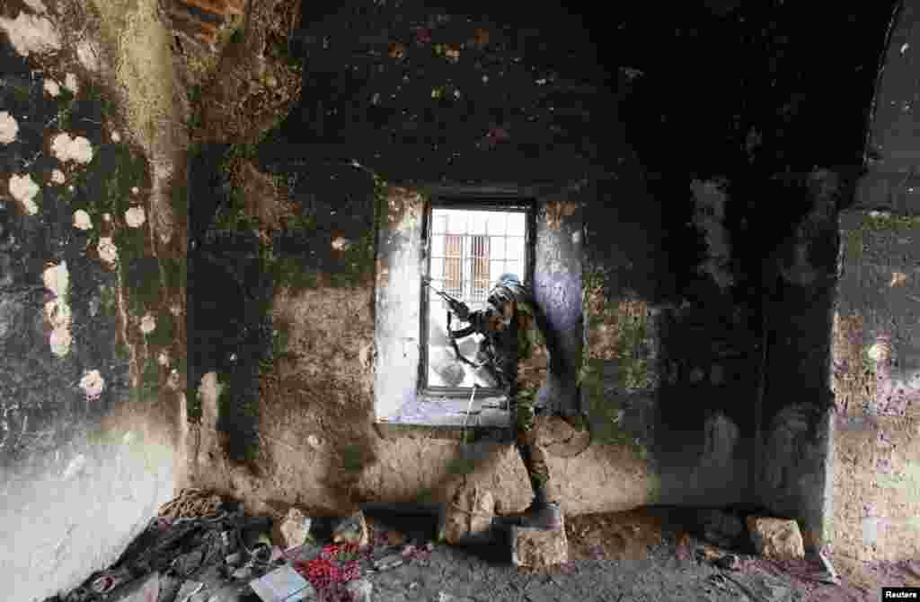 A Free Syrian Army fighter looks through a window of a damaged house in Old Aleppo, Dec. 15, 2013. 