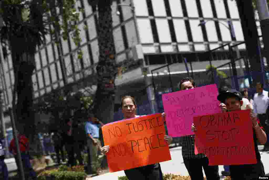People hold signs calling for the U.S. government to halt deportations of immigrants during a protest ahead of U.S. President Barack Obama's visit, outside the U.S. embassy in Mexico City, May 2, 2013. 