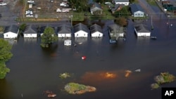 FILE - Floodwaters from Hurricane Florence surround homes in Dillon, S.C., Sept. 17, 2018. Scientists say climate change likely boosted rainfall totals for both Florence and 2017's Harvey. 