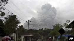 Motorists ride as pyroclastic material from the eruption of Mount Merapi billows in the background in Cangkringan, Yogyakarta, Indonesia, 31 Oct 2010
