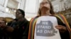 FILE - The Rev. Annie Steinberg-Behrman, right, provisional pastor with Metropolitan Community Church, holds a sign while listening to speakers at a meeting at City Hall in San Francisco to reaffirm the city's commitment to being a sanctuary city, Nov. 14, 2016.
