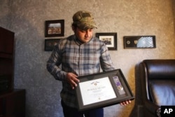 FILE - Zia Ghafoori displays the Purple Heart at his home in Charlotte, N.C., that he received while working with U.S. Forces in Afghanistan, Dec. 16, 2019. He received a Special Immigrant Visa in 2014 and is working toward becoming a U.S. citizen.