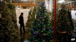 In this Friday, Nov. 30, 2018, photo, a man looks at artificial Christmas trees for sale at the Balsam Hill Outlet store in Burlingame, Calif. (AP Photo/Eric Risberg)