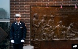 Seorang petugas pemadam kebakaran New York City berdiri di depan gambar peringatan di sisi kantor pemadam kebakaran yang berdekatan dengan One World Trade Centre dan tugu Peringatan 9/11 di New York, 11 September 2018.