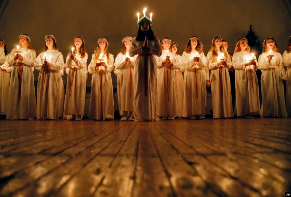 Young women sing songs as they hold candles to celebrate St. Lucia's Day in the Evangelical Lutheran Church of Saint Katarina in St. Petersburg, Russia.