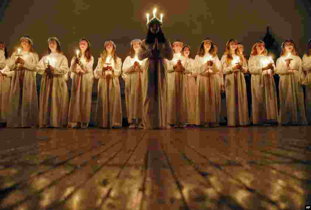 Young women sing songs as they hold candles to celebrate St. Lucia&#39;s Day in the Evangelical Lutheran Church of Saint Katarina in St. Petersburg, Russia.
