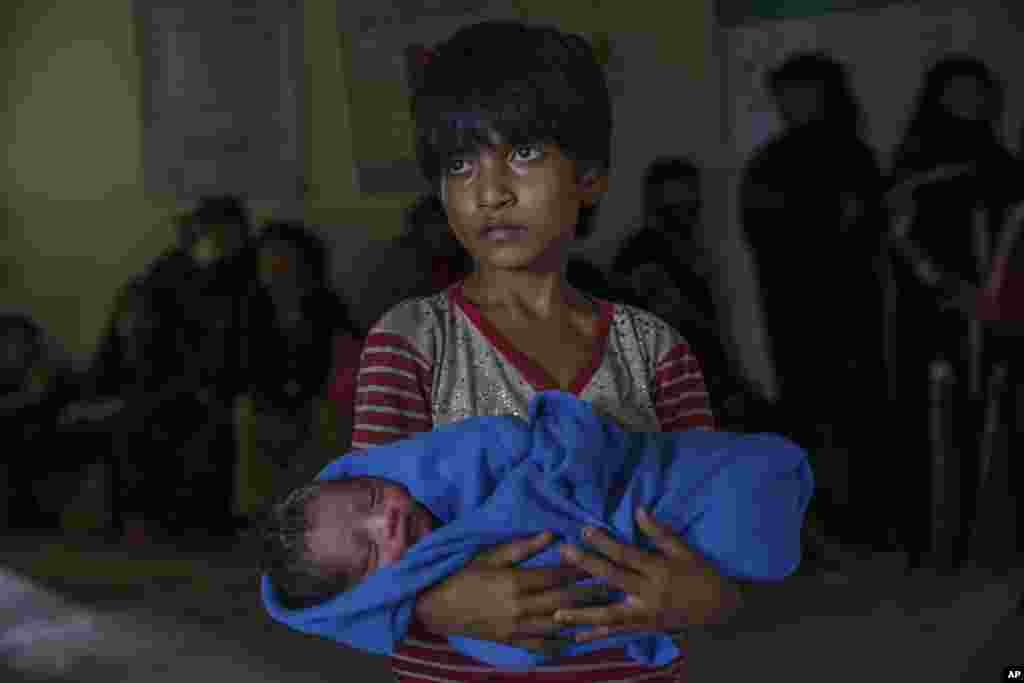 دختر بچه آواره روهینگیایی که برادر تازه متولد شده اش را در آغوش کشیده. او و هزاران نفر در درگیری گروه مسلمانان مسلح به نام آراکان و ارتش میانمار آواره شده اند.