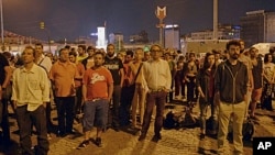 Erdem Gunduz, left, and dozens of people stand silently on Taksim Square in Istanbul early Tuesday, June 18, 2013.