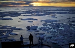 FILE - Researchers look out from the Finnish icebreaker MSV Nordica as the sun sets over sea ice in the Victoria Strait along the Northwest Passage in the Canadian Arctic Archipelago, July 21, 2017.