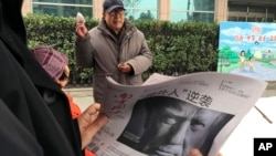 FILE - A Chinese man holds up a Chinese newspaper with the front-page photo of Donald Trump and the headline "Outsider counter attack" at a newsstand in Beijing, China, Nov. 10, 2016. China has pledged to "firmly defend its legitimate rights and interests" regarding U.S. tariffs on steel and aluminum.