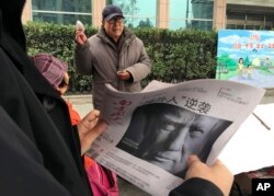FILE - A man holds a Chinese newspaper with a front page photo of U.S. President Donald Trump at a newsstand in Beijing, China, Nov. 10, 2016. China has pledged to "firmly defend its legitimate rights and interests" in response to metal tariffs intruduced by the Trump administration.