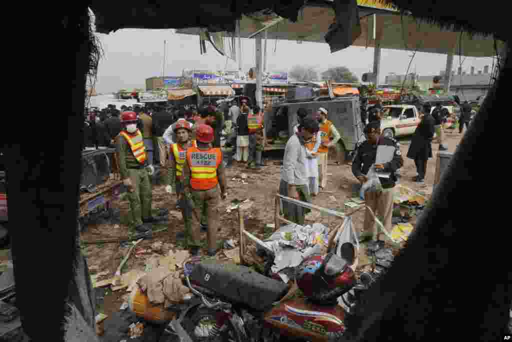 Police officers and volunteers visit the site of a blast in Peshawar, Pakistan, March 14, 2014. 