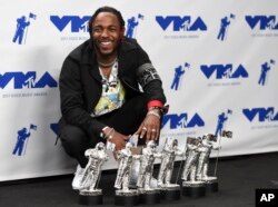 Kendrick Lamar poses in the press room with the awards for best hip hop video, best direction, best cinematography, best art direction, best visual effects, and video of the year for "HUMBLE." at the MTV Video Music Awards, Aug. 27, 2017, in Inglewood, Ca