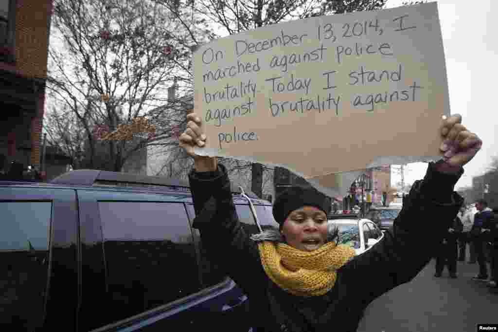 Seorang perempuan memegang poster di tempat peringatan dadakan di lokasi penembakan dua polisi di Brooklyn, New York, 22 Desember 2014.