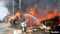 12일 잠보앙가시에서 시민이 공격으로 불이난 집에 물을 뿌리고 있다. 