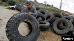 FILE - Palestinian man Abdulrahman Al-Skafi, 54, rolls an old vehicle tire to make buckets out of it, in Hebron in the Israeli-occupied West Bank February 19, 2019. (REUTERS/Raneen Sawafta)