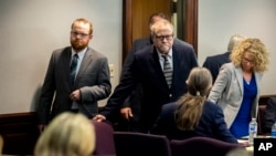 Greg McMichael, center, and his son, Travis McMichael, left,, look at family members seated in the gallery when they walk into the courtroom for the reading of the jury's verdict in the Glynn County Courthouse, Nov. 24, 2021, in Brunswick, Ga. 