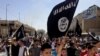 File - Demonstrators chant pro-Islamic State group slogans as they wave the group's flags in front of the provincial government headquarters in Mosul, Iraq, June 2014.