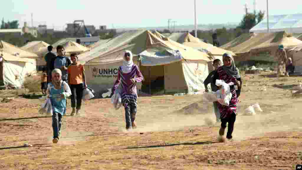 Syrian refugee children run while carrying traditional gifts of toys and clothes they received from individual donors and international organizations on the first day the Muslim holiday of Eid al- Fitr at the Zaatari Refugee Camp in Mafraq, Jordan, Aug. 1
