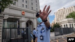 当押送任志强的警车抵达北京第二中级人民法院时一名警察在向记者做手式。（2020年9月11日）