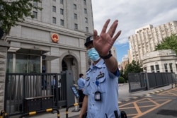 当押送任志强的警车抵达北京第二中级人民法院时一名警察在向记者做手式。（2020年9月11日）
