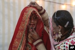 FILE - A woman helps a Pakistani Hindu bride prepare for her wedding in Karachi, Pakistan.