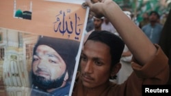 FILE - A supporter of a religious political party holds a banner of convicted killer Mumtaz Qadri during a demonstration against Qadri's sentence, in Karachi, March 9, 2015. 