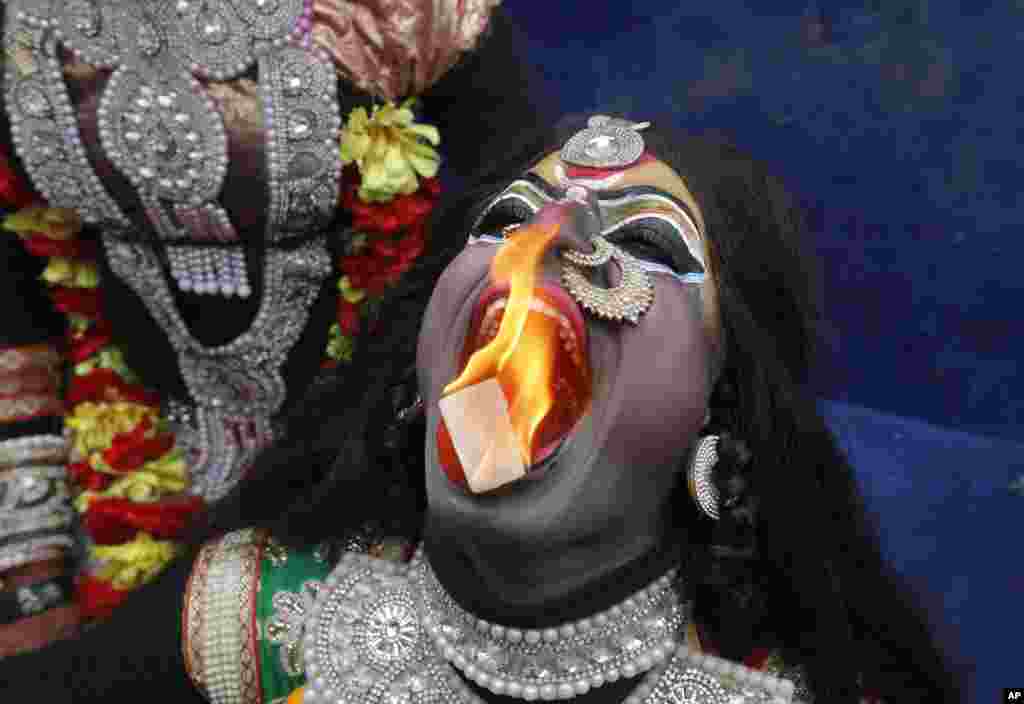 인도 알라하바드에서 열린 마하쉬브라트리 축제에서 힌두교 칼리 신으로 분장한 남성이 불 공연을 펼치고 있다.