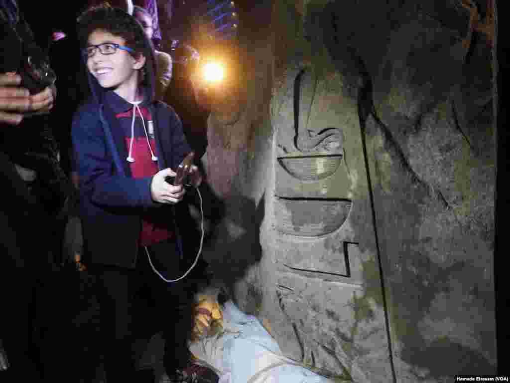 An Egyptian child takes an image of the carving found on the back of the statue that was discovered recently in Matarya that almost certainly depicts Psamtik I, March 16, 2017. (H. Elrasam/VOA)