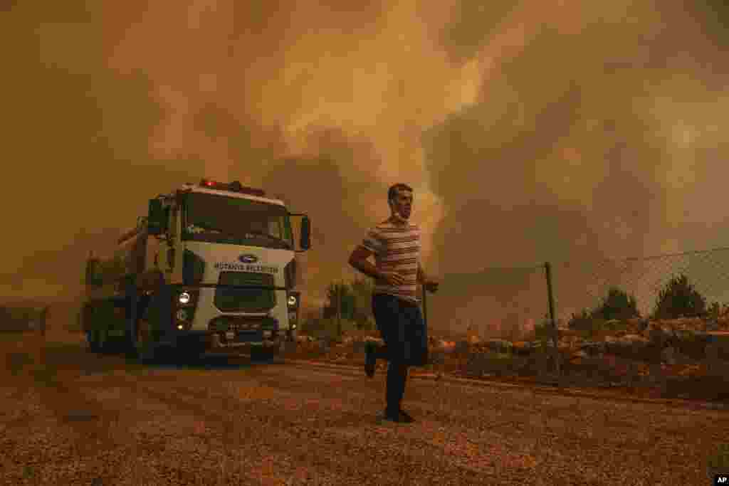 A man runs in the fire-devastating Sirtkoy village, near Manavgat, Antalya, Turkey. More than 100 wildfires have been brought under control in Turkey, according to officials.