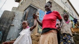 In this Sunday, May 3, 2020 file photo, Margaret Andeya takes her daughter Gettrueth Ambio, 12, right, and her neighbor's daughter Jane Mbone, 7, left, back home after having their hair styled in the shape of the new coronavirus.