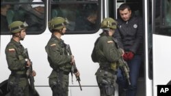 El supuesto narcotraficante Daniel Barrera, alias "El Loco Barrera", baja de un bus camino a su presentación ante los medios en una estación de policía en Bogotá, Colombia.