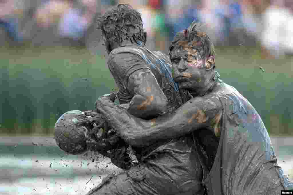 Participants fight for the ball during a handball match at the so called &quot;Wattoluempiade&quot; (Mud Olympics) in Brunsbuettel at the North Sea, Germany, July 30, 2016.