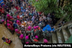 Warga terdampak banjir berkumpul untuk meminta bantuan dari Presiden RI Joko Widodo di Desa Pekauman Ulu, Kabupaten Banjar, Provinsi Kalimantan Selatan, 18 Januari 2021. (Foto: Antara/Bayu Pratama via Reuters)
