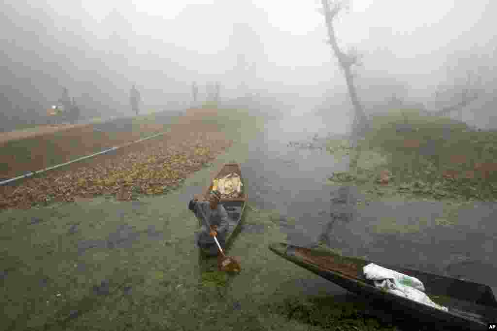 A man rows his boat in the Dal Lake surrounded by dense fog on a cold morning in Srinagar, Indian-controlled Kashmir.