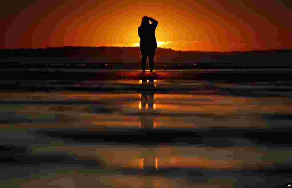 Consuello Jessop, of Providence, Rhode Island, photographs the sunrise at Ocean Park in Old Orchard Beach, Maine.