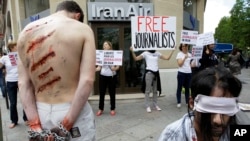 FILE - Reporters Without Borders activists, bound and made up as mock victims, demonstrate outside the Iran Air office on the Champs Elysées in Paris, July 10, 2012, to protest the imprisonment of Iranian journalists.