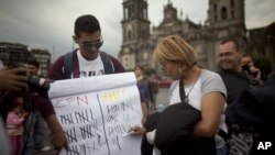 Jóvenes mexicanos muestran en el Zócalo de la capital un cartel con la puntuación de los candidatos presidenciales, según sondeos.