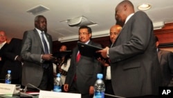 Nhial Deng Nhial (left) of South Sudan's negotiating team and Taban Deng Gai (right), negotiator for Riek Machar's rebel group, exchanged signed cessation of hostilities agreements in Addis Ababa one year ago, but South Sudan is still mired in conflict.