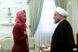 In this photo released by the official website of the office of the Iranian Presidency, Iran's President Hassan Rouhani, right, greets European Union foreign policy chief Federica Mogherini at the president's office in Tehran, Iran, July 28, 2015.