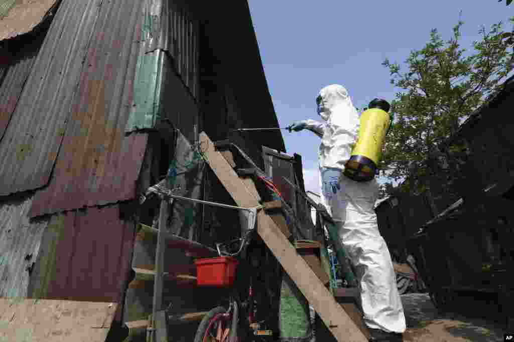 An employee of the non-profit Cambodian Children's Fund sprays disinfectant to help curb the spread of the new coronavirus in the slum neighborhood of Stung Meanchey in southern Phnom Penh, Cambodia, on Tuesday, March 24, 2020. (AP Photo/Heng Sinith)