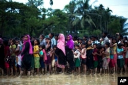 FILE - Rohingya Muslims, who crossed over recently from Myanmar into Bangladesh, wait to receive food being distributed near Balukhali refugee camp in Cox's Bazar, Bangladesh, Sept. 19, 2017. In a speech Tuesday, Myanmar's de facto leader, Aung San Suu Kyi, claimed that "the world is totally unaware" that not just Muslims but also Buddhists and members of various minority sects have had to flee the violence in Rakhine state.