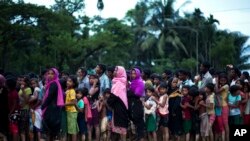 FILE - Rohingya Muslims, who crossed over recently from Myanmar into Bangladesh, wait to receive food being distributed near Balukhali refugee camp in Cox's Bazar, Bangladesh, Sept. 19, 2017.