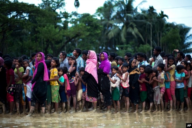 FILE - Rohingya Muslims, who crossed over recently from Myanmar into Bangladesh, wait to receive food being distributed near Balukhali refugee camp in Cox's Bazar, Bangladesh, Sept. 19, 2017. In a speech Tuesday, Myanmar's de facto leader, Aung San Suu Kyi, claimed that "the world is totally unaware" that not just Muslims but also Buddhists and members of various minority sects have had to flee the violence in Rakhine state.