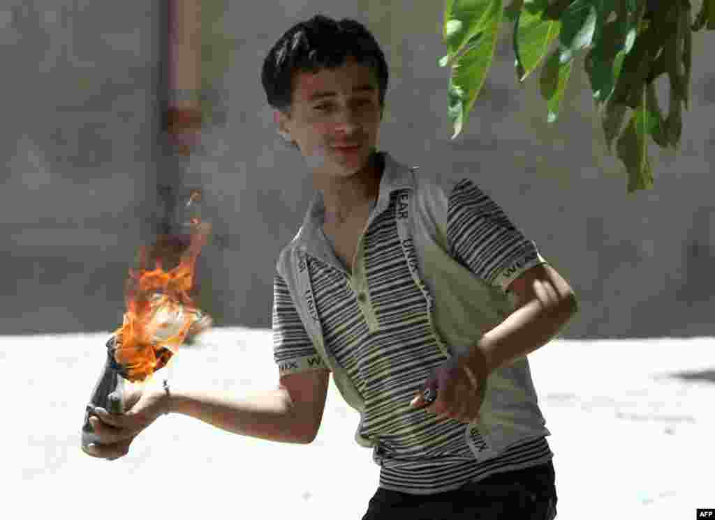 A Palestinian boy readies to throw a flaming molotov cocktail towards Israeli soldiers deployed at the entrance of the al-Aroub Palestinian refugee camp, May 15, 2012.