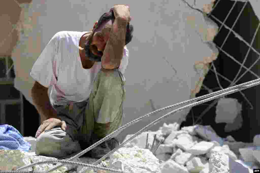 A man looks on as Syrian civil defense workers look for survivors under the rubble of a collapsed building following reported air strikes in the rebel-controlled neighbourhood of Karm Homad in the northern city of Aleppo.